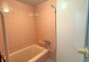 a bathroom with a tub and a shower with pink tiles at Nishijin Stay One in Fukuoka +12 photos