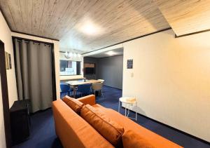 a living room with an orange couch and a table at Nishijin Stay One in Fukuoka