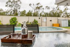 a bottle and glasses on a table next to a pool at The Salty Anchor in Banksia Beach