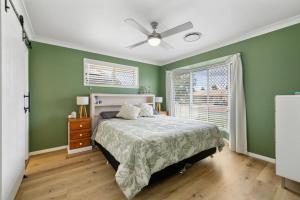 a green bedroom with a bed and a ceiling fan at The Salty Anchor in Banksia Beach +11 photos