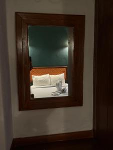 a mirror on a wall with a bed in a room at Hotel las Orquideas in Valle de Bravo