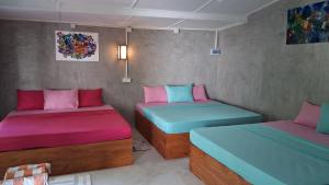 two beds in a room with pink and blue at Beach Lovers Tiny House in Nilaveli