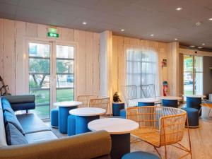 a waiting room with tables and chairs and a couch at ibis Manosque Cadarache in Manosque