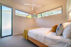 a bedroom with a bed with a ceiling fan and windows at Gumleaf Villa Hosted by Halls Gap Accommodation in Halls Gap
