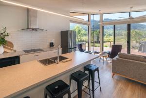 a kitchen and living room with a counter and stools at Gumleaf Villa Hosted by Halls Gap Accommodation in Halls Gap