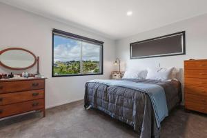 a bedroom with a bed with a dresser and a window at Cable Bay Serenity in Cable Bay
