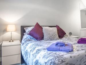 a bedroom with a bed with purple sheets and pillows at Corner Spot in Hednesford
