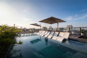 a pool with white lounge chairs and an umbrella at Heritage Ham Long Hotel and Spa in Hanoi