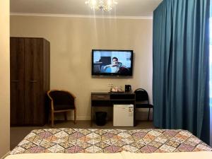 a bedroom with a tv and a bed and a desk at Silk Way in Almaty