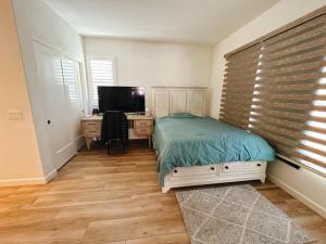 a bedroom with a bed and a desk with a television at FB Master in Irvine