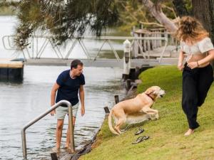 a man and a woman and a dog by the water at Tasman Holiday Parks - Jervis Bay in Huskisson