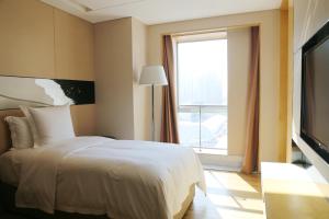 a bedroom with a white bed and a window at Langham Place Xiamen in Xiamen