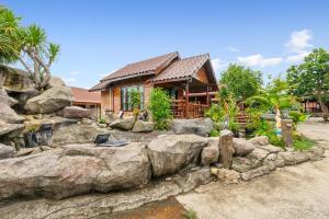 a home with a rock wall in front of a house at Chanta Boutique Place in Ubon Ratchathani