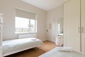 a white bedroom with a bed and a window at Cozy Connemara Family Retreat in Derroogh
