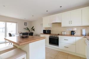 a kitchen with white cabinets and a wooden counter top at Cozy Connemara Family Retreat in Derroogh