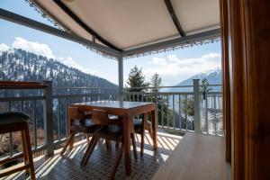 a table and chairs on a balcony with a view at Hamta 270 Cliff Resort - 270 Degree Mountain View Suites, Sethan Manali in Manāli