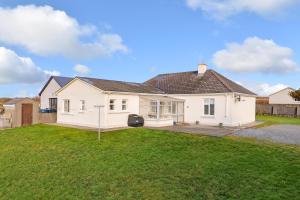 a white house with a lawn in front of it at Cozy Connemara Family Retreat in Derroogh