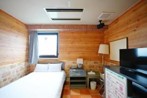 a small bedroom with a bed and a television at ホテル韮崎インター in Nirasaki