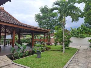 a garden with a pavilion and a palm tree at Omah Pinter in Beran-kidul