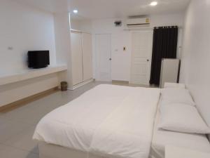 a bedroom with a large white bed and a tv at Illusion Hostel & Club in Pattaya South