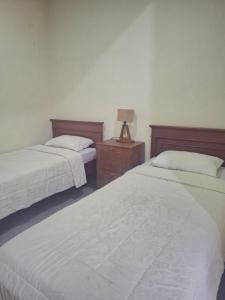 a bedroom with two beds and a lamp on a night stand at Omah Pinter in Beran-kidul
