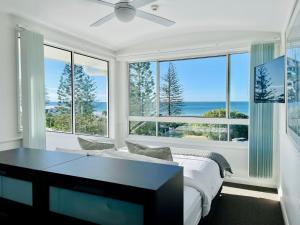 a bedroom with a bed and a table and windows at Alex Beach Front Nest in Alexandra Headland