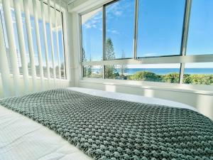 a bedroom with a bed with a view of the ocean at Alex Beach Front Nest in Alexandra Headland