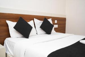 a bed with black and white pillows on it at Stay Prime, Balewadi in Pune