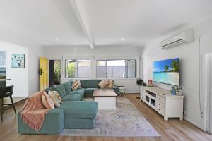a living room with a green couch and a table at Mermaid Cottage in Hawks Nest
