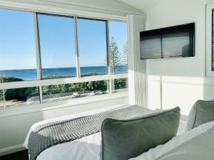 a bedroom with a view of the ocean from a window at Alex Beach Front Nest in Alexandra Headland