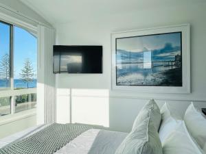 a bedroom with a bed and a tv on the wall at Alex Beach Front Nest in Alexandra Headland