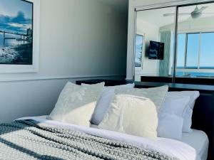 a bedroom with a bed with white pillows and a window at Alex Beach Front Nest in Alexandra Headland +37 photos