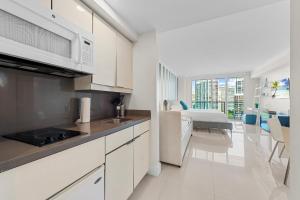 a kitchen with white cabinets and a living room with a bed at Arya Hotel & Suites in Miami