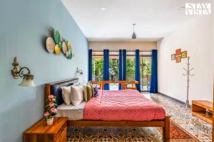 a bedroom with a bed with a red bedspread and blue walls at StayVista at Aradhya Villa with Infinity Pool, Lawn in Wayanad +23 photos