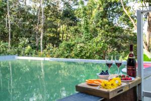 a table with two glasses of wine and some fruit at StayVista at Aradhya Villa with Infinity Pool, Lawn in Wayanad