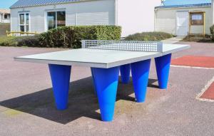a ping pong table with blue legs in a parking lot at Mobile-Home Proche Mer 400M in Grandcamp-Maisy