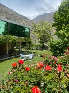 a garden with red roses in front of a building at Gahirat Castle Chitral in Chitral
