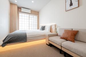 a bedroom with a bed and a couch and a window at b&黒門3号店 in Osaka