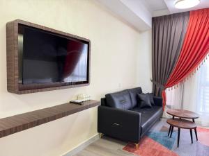 a living room with a black couch and a flat screen tv at Inap II, Suterabay By Ayuhouz in Kota Kinabalu