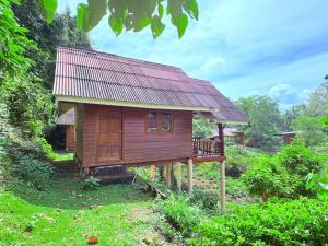 a small wooden house with a deck in a field at Namtok Bungalows in Ko Yao Noi
