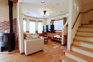 a living room with a staircase and a fireplace at KOGUMA AKIRUNO villa in Akiruno