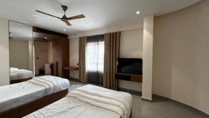 a hotel room with two beds and a flat screen tv at Cloud Nine Hotel - Kuthuparamba in Kūttuparamba