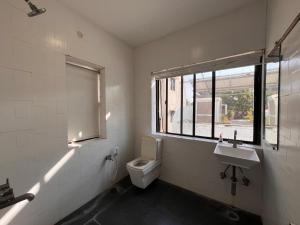 a bathroom with a toilet and a sink and a window at Urban Nest in Nagpur