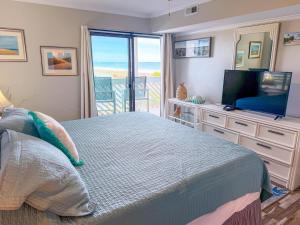 a bedroom with a bed and a television and a balcony at Ocean Shores 301 in North Myrtle Beach +27 photos