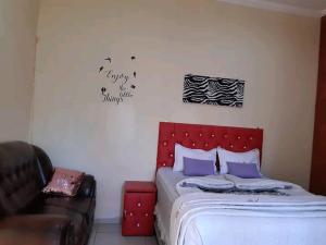 a bedroom with a bed with a red headboard and a couch at Dne Blue Star in Klerksdorp