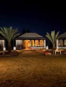 a building with a pavilion with palm trees in front of it at Sahara Gift camp in Merzouga