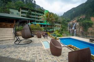 a resort with a pool and chairs and a waterfall at Ramboda Falls PLC in Ramboda