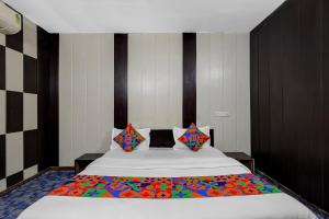 a bedroom with a large bed with colorful sheets and pillows at FabHotel Aavkar in Sātej