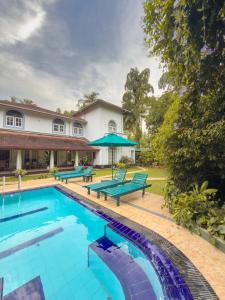 a swimming pool with benches and a house at Villa House in Miriswatta