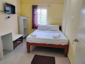 a small bedroom with a bed and a bathroom at ISIRI Rooms in Mysore